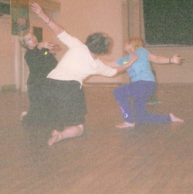 Three dancers kneeling in a circle